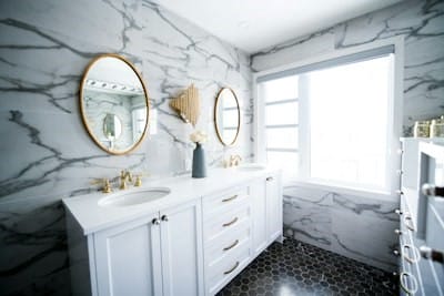 double sink vanity with gold round mirrors and marble walls